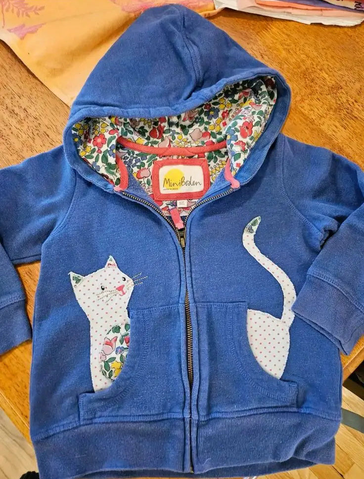 Blue hoodie with cat design on a wooden surface