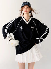 Person wearing a black oversized sweater with white stripes and a white skirt