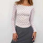 White long-sleeve top with red polka dots worn by a model