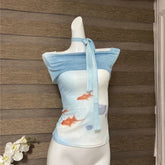 Mannequin wearing a blue and white top with fish design against a wooden panel background