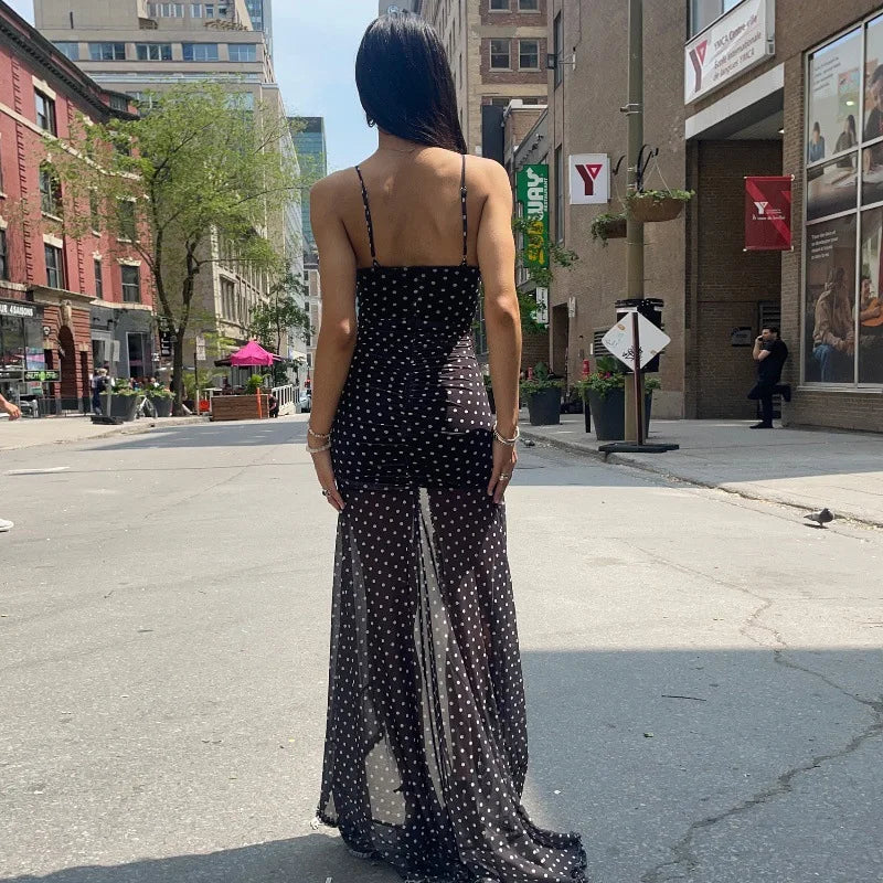 Woman in a black polka dot dress standing on a city street
