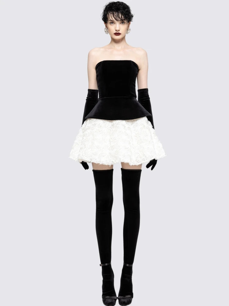 Woman wearing a black and white dress with black gloves and stockings