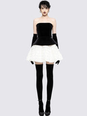 Woman wearing a black and white dress with black gloves and stockings