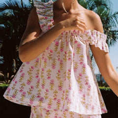 Woman wearing a floral off-shoulder dress with a blurred face, standing outdoors.