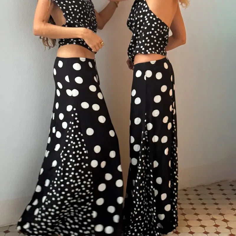 Woman wearing a black and white polka dot outfit with wide-leg pants, standing against a plain background.