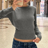 Person wearing a gray sweater and blue jeans in an indoor setting