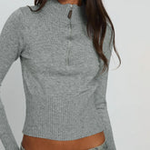 Gray long-sleeve top worn by a person on a plain background