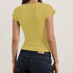 Person wearing a yellow cap-sleeve top and blue jeans on a plain background