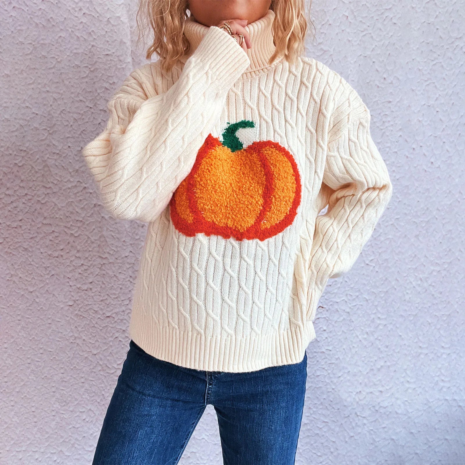 Person wearing a cream sweater with a pumpkin design