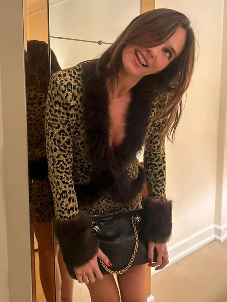 Woman wearing a leopard print jacket with fur trim in front of a mirror.