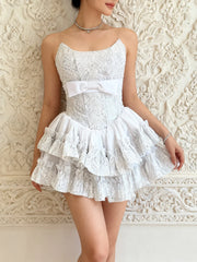 White lace dress with a bow belt worn by a person against an ornate wall.