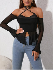 Woman wearing a black top with sheer sleeves and blue jeans against a neutral background