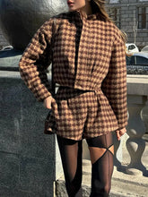 Person wearing a brown checkered outfit standing outdoors.
