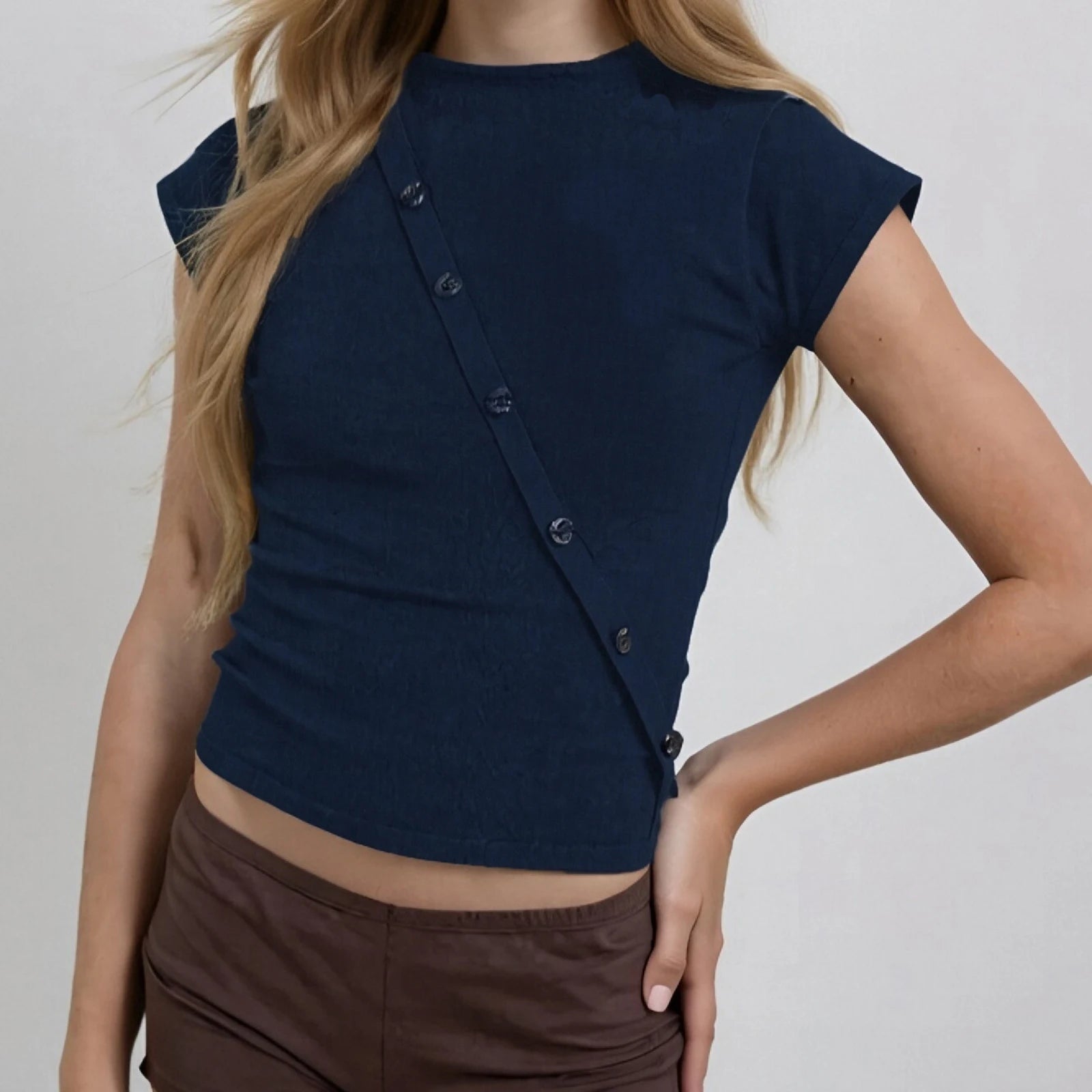 Navy blue top with button details worn by a person on a plain background