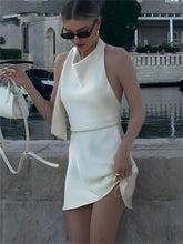 Woman in a white outfit standing by a waterfront with boats in the background