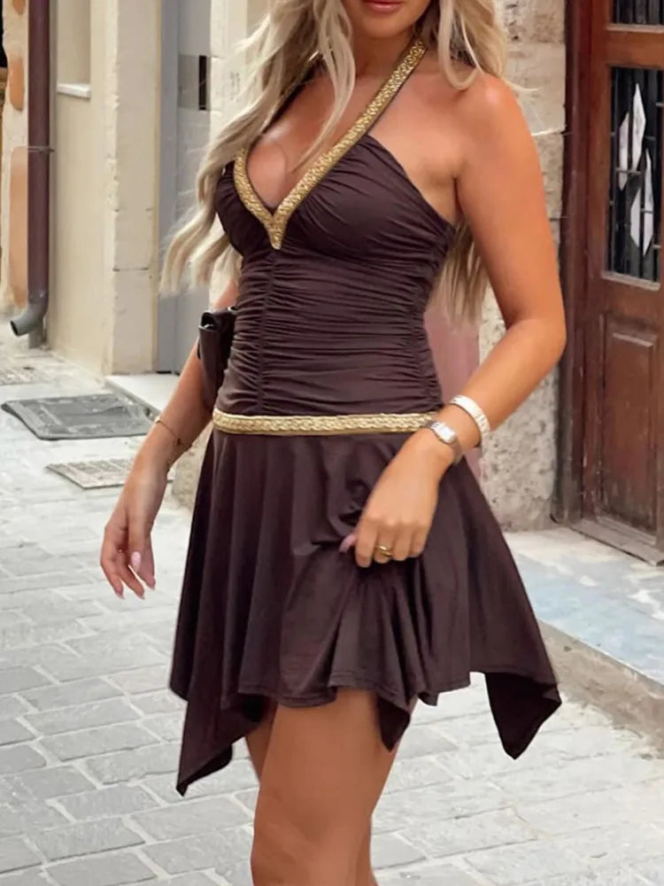 Woman wearing a brown one-shoulder dress with gold accents on a street.