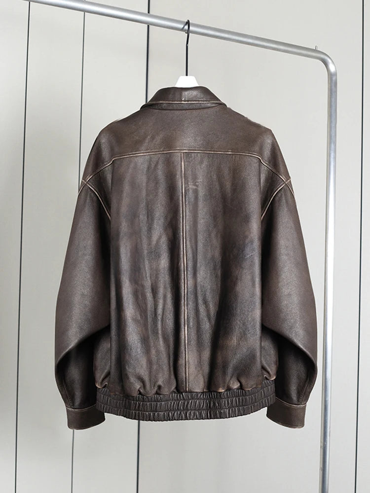 Brown leather jacket on a hanger against a white wall
