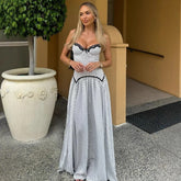 Woman in a polka dot dress standing outdoors next to a large planter.