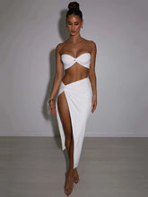 Woman wearing a white strapless top and skirt against a plain background