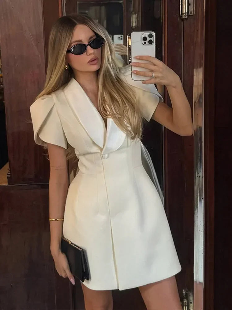 Woman taking a mirror selfie wearing a white outfit.