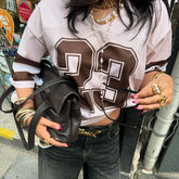 Person wearing a white and brown sports jersey with large numbers, holding a black bag.