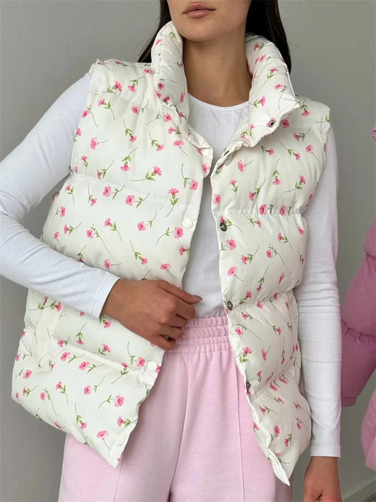 Person wearing a floral patterned puffer vest over a white shirt and pink pants.