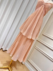 Pink pleated dress on a mannequin against a white curtain background