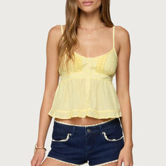 Woman wearing a yellow top and denim shorts on a white background