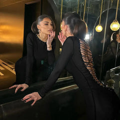 Two women in formal attire interacting in a stylish indoor setting.