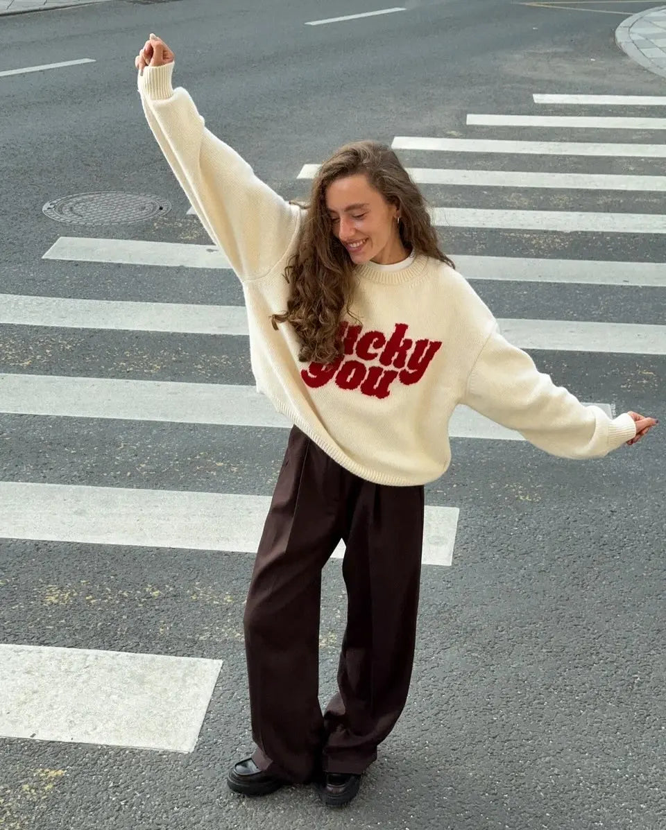 Person wearing a white sweater with red text on a crosswalk