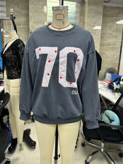 Gray sweatshirt with '70' print on a mannequin in a store setting