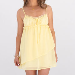 Yellow lace-trimmed dress worn by a person on a white background