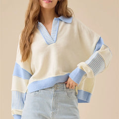 Woman wearing a cream and blue sweater with a neutral background