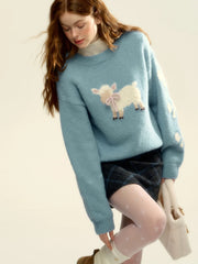 Woman wearing a light blue sweater with a sheep design