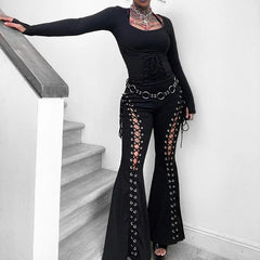 Person wearing a black outfit with lace-up details standing on a staircase.