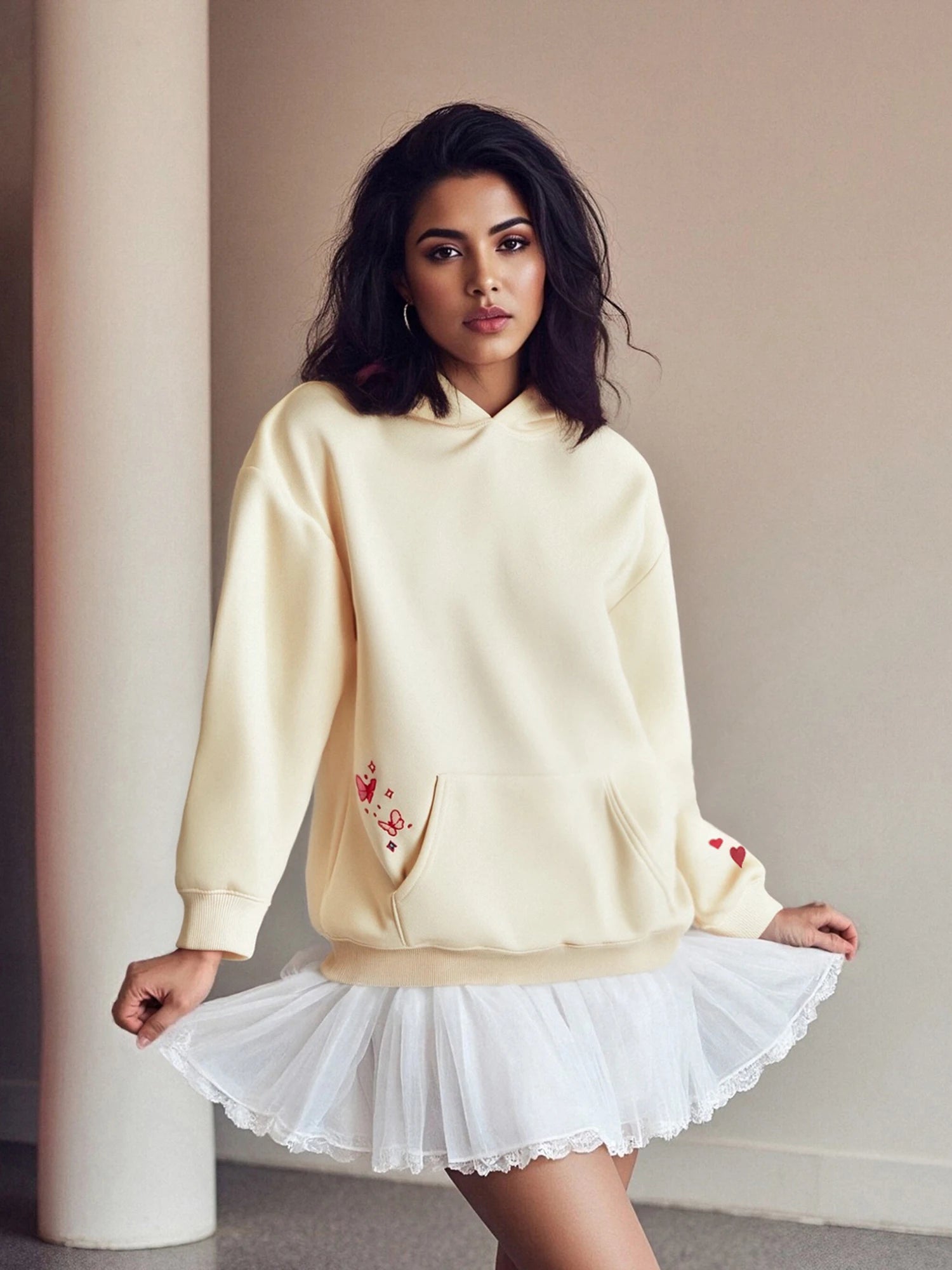 Woman wearing a light yellow sweatshirt with floral embroidery and a white skirt
