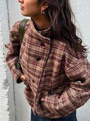 Person wearing a plaid jacket against a light gray wall