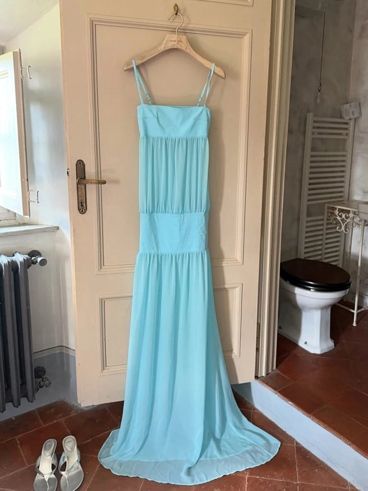 Light blue dress hanging on a door in a room with a toilet and radiator.