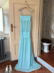 Light blue dress hanging on a door in a room with a toilet and radiator.
