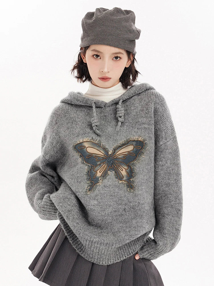 Person wearing a gray sweater with a butterfly design