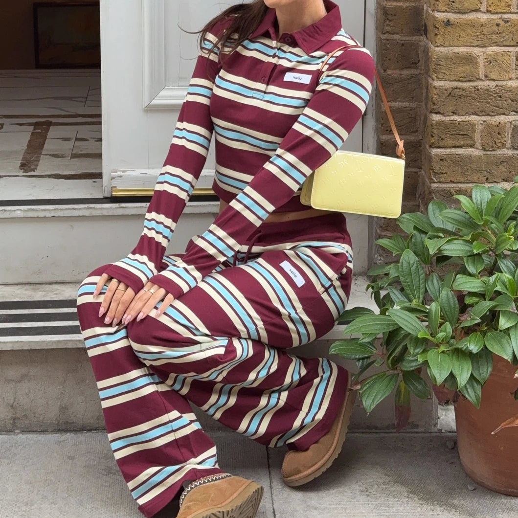 Person wearing a maroon and blue striped outfit sitting on steps with a yellow bag.
