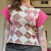 Person wearing a patterned top with pink sleeves and a geometric design.
