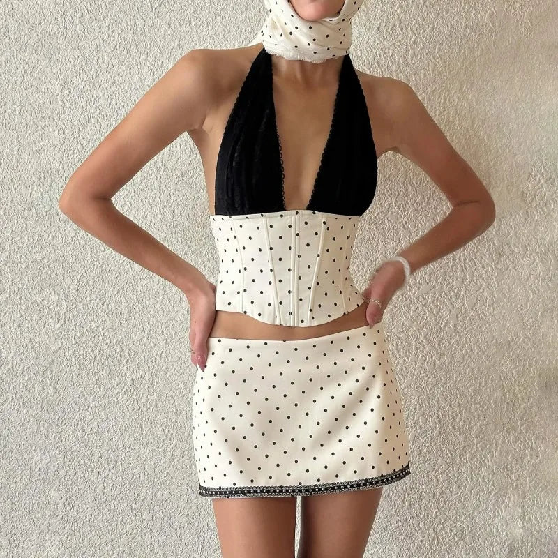 Person wearing a black and white polka dot dress against a plain background