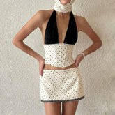 Person wearing a black and white polka dot dress against a plain background