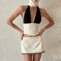 Person wearing a black and white polka dot dress against a plain background