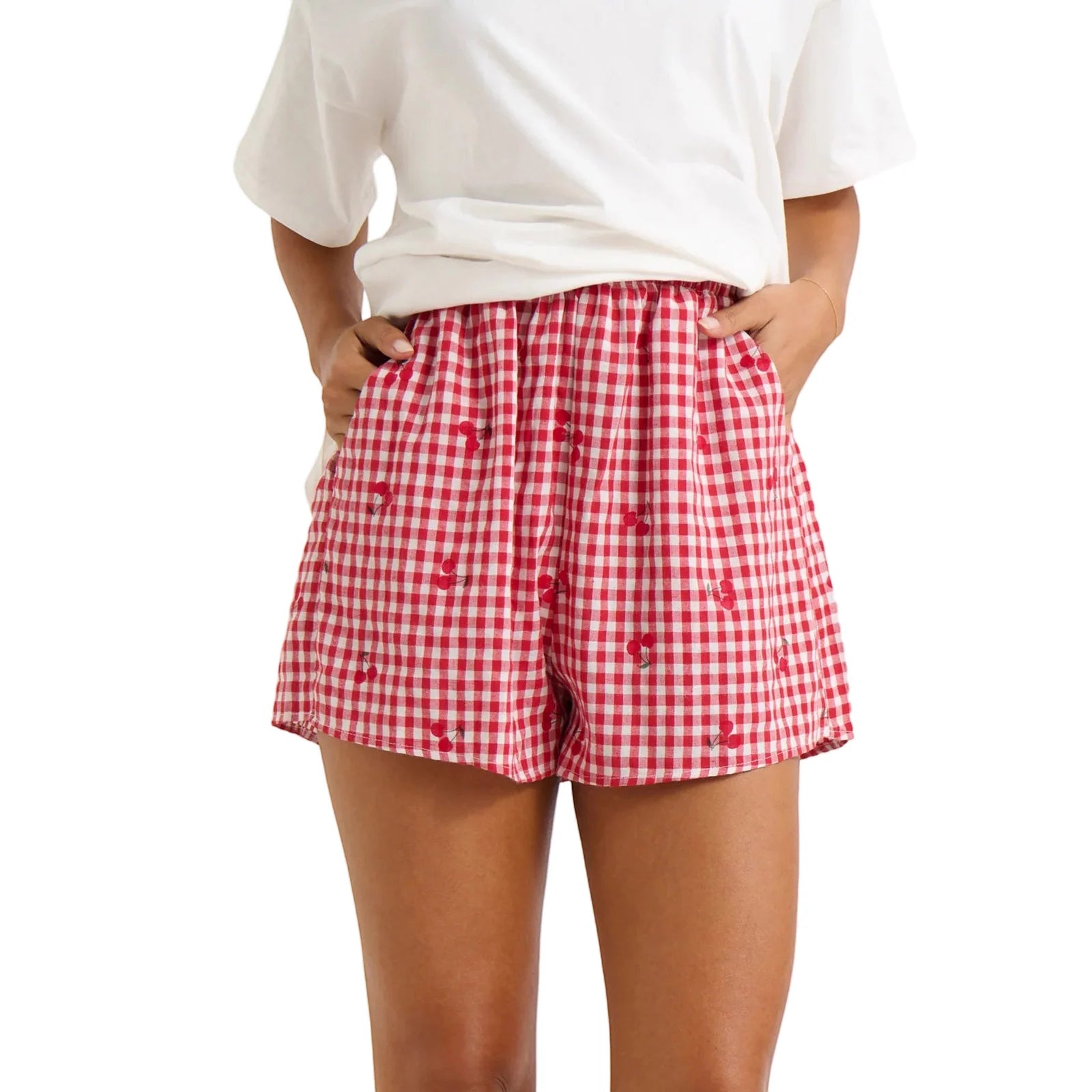 Model displaying red plaid shorts with cherry print and an elastic high waist.