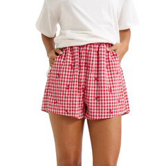 Model displaying red plaid shorts with cherry print and an elastic high waist.