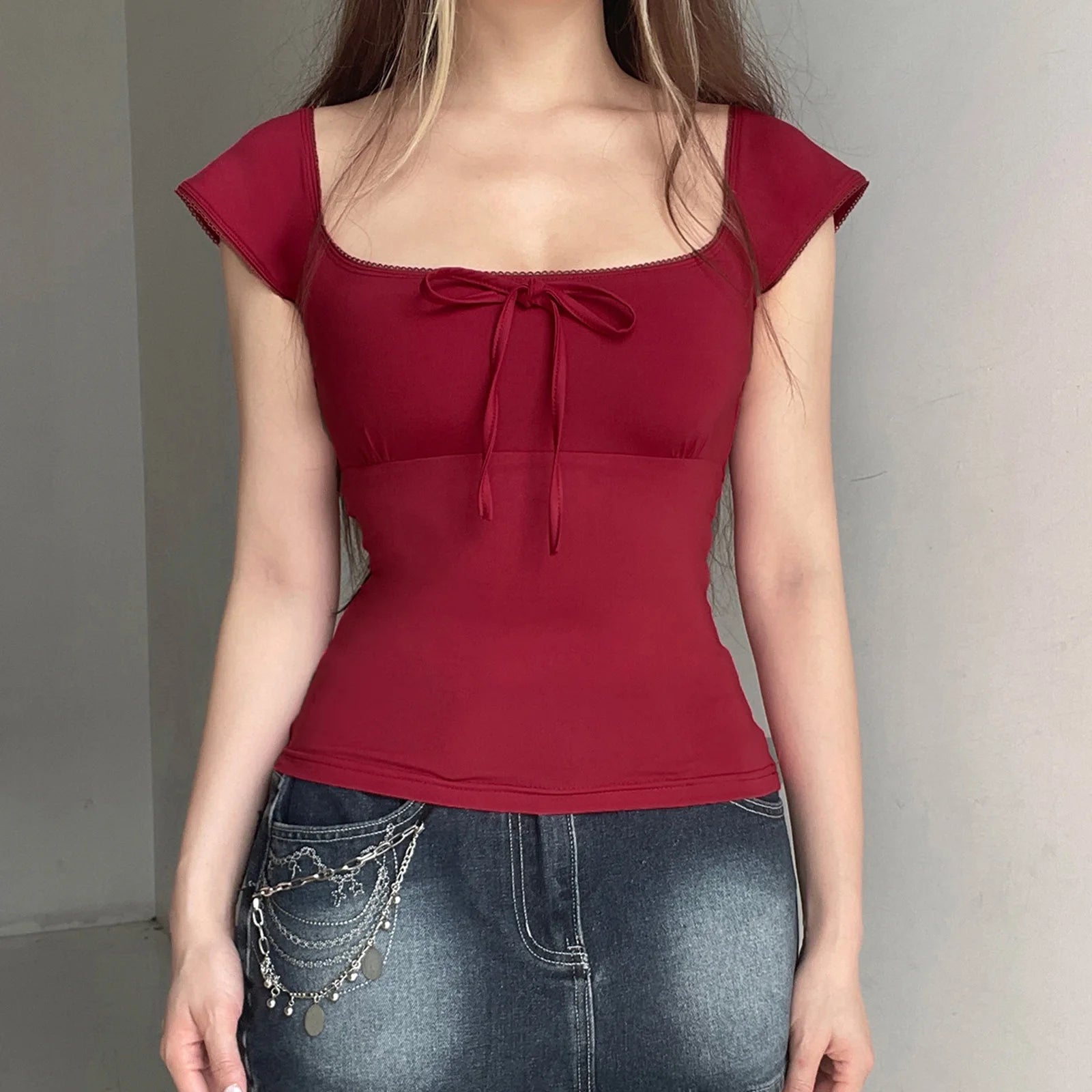 Red top with a bow detail worn by a person against a neutral background