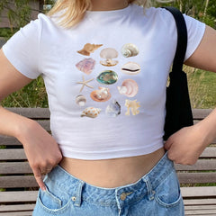 Person wearing a white t-shirt with shell designs outdoors