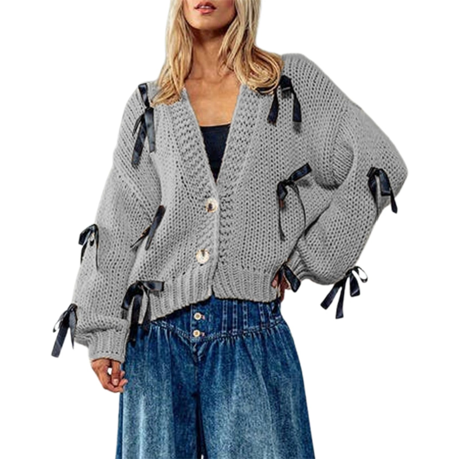 Woman wearing a gray knitted cardigan with black ribbons and blue jeans